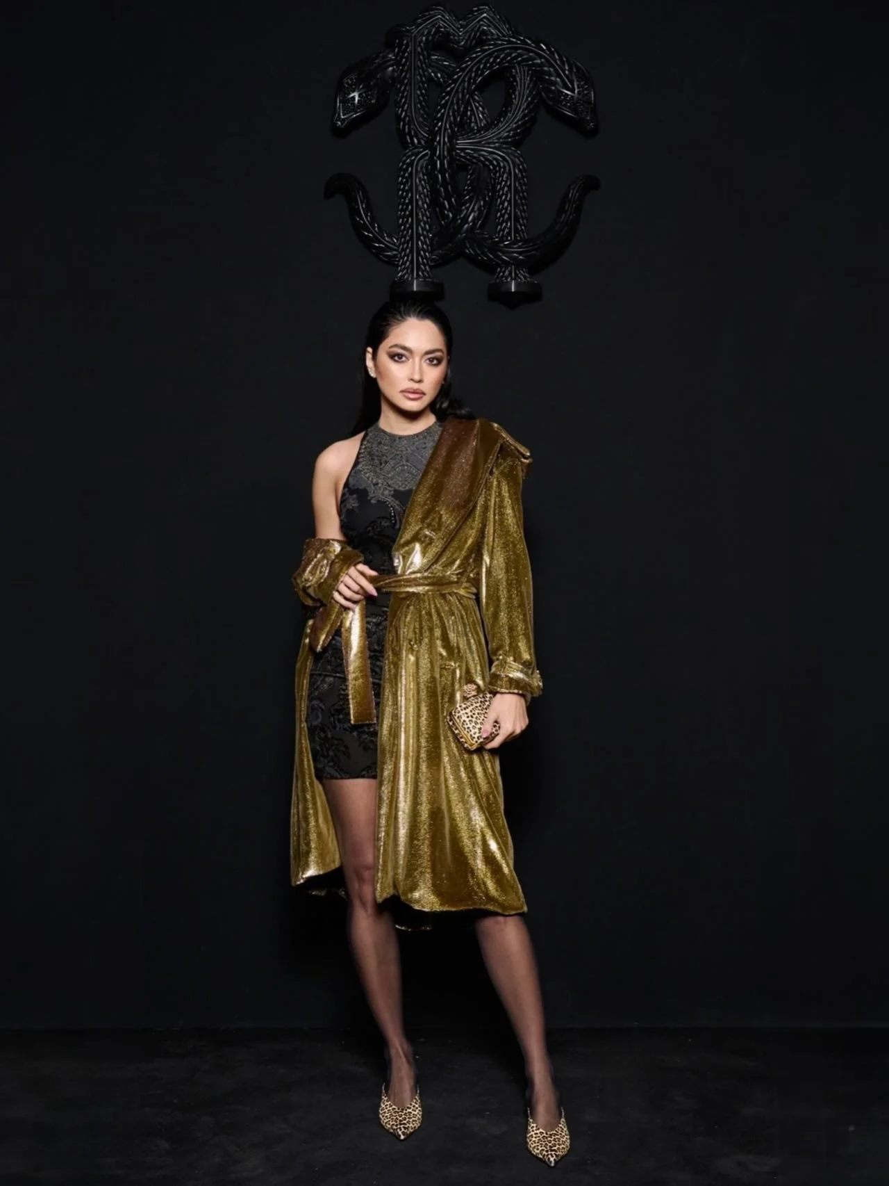 Still obsessed with this look, wearing a black mini dress with a close-fitting crew neckline, featuring the Ornamental Black print. The look is completed with a gold trench coat, kitten heels and a Roar clutch in baby j...